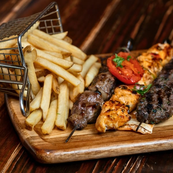 Sirocco's mixed grill platter with chicken, beef, and kofta kebabs, fries, and grilled tomatoes.